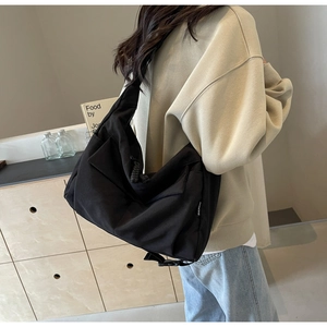 Detailed view of the large black canvas tote bag worn by a model in a modern room