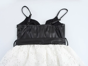 Détail d'une robe en cuir PU noir avec un patchwork de dentelle blanche complexe au dos