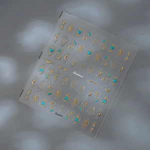 Detail of gold and turquoise nail stickers with stars, moon patterns and fashion text