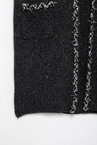 Détail de l'ourlet de robe en tweed noir avec paillettes argentées et bordure de perles