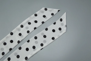 Detailed view of white chiffon ribbon with black polka dots and slanted edge cut