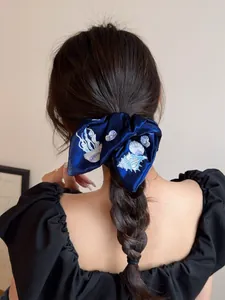 Detail of dark blue velvet scrunchie with sea creature embroidery on a braided ponytail