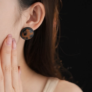 Gros plan d'une boucle d'oreille léopard avec bord noir portée par un mannequin