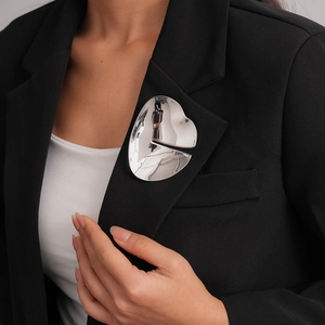 Close-up of a large silver irregular abstract brooch on a black blazer lapel