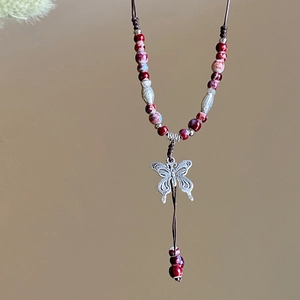 Detail showing handwoven rope with a silver butterfly pendant and ceramic beads
