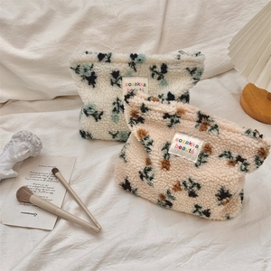 Detail of plush floral cosmetic bags with zip closure and colorful brand labels