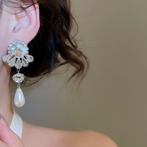 Detail of silver flower stud earrings with hanging teardrop pearl and sparkling crystals