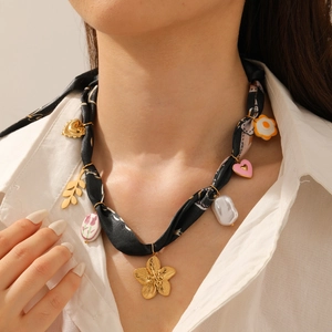 Detail of silk scarf necklace featuring gold floral charms and heart pendant accents