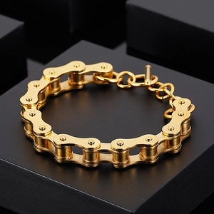 Detailed close-up of golden bicycle chain bracelet with T-bar clasp on black geometric background