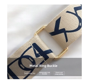 Detail of light gold metal buckle and cream woven strap with navy blue lettering