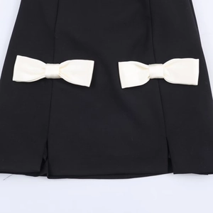 Mini robe noire avec deux nœuds en satin blanc et détails de fentes symétriques