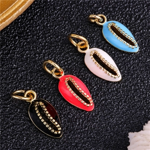 Macro shot of shell pendants in four colors with gold borders on black texture