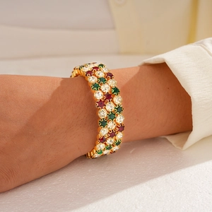 Detail of gold triple-layered bangle with red, green, and white pavé-set gemstones