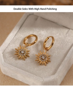 Detail of gold sunburst drop earrings with inlaid sparkling cubic zirconia on beige velvet