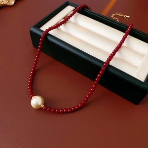 Détail du collier de perles rouges avec pendentif perle dorée sur un écrin à bijoux noir