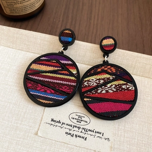 Detail of bohemian round geometric earrings with colorful woven fabric inlay