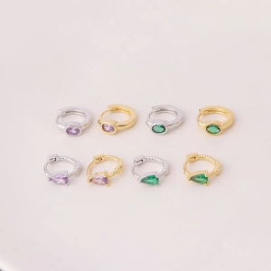 Detail of gold and silver hoop earrings with purple and green teardrop zircons