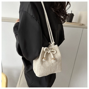 Detail of hand-woven cream bucket bag with thick rope strap and gold metal hardware accents