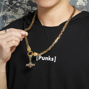Close-up of golden Viking Mjolnir pendant with skull detail and Byzantine chain on model