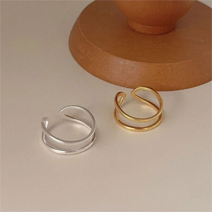 Detailed top view of gold and silver double-layered minimalist open rings on wood stand