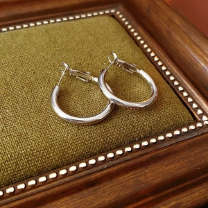 Classic silver hoop earrings displayed on a vintage jewelry box with green cushion