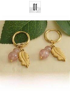 Detail of 18k gold-plated feather earrings with soft pink natural stone on fabric