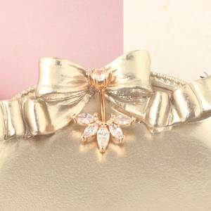 Macro detail of rose gold belly ring featuring a marquise-cut zircon flower cluster