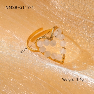 Macro shot of gold heart open ring with white beads on gold silk fabric background