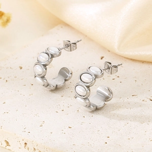 Detail of silver C-shaped hoop earrings with inlaid white mother-of-pearl on stone