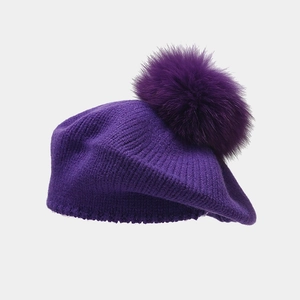 Detail of purple knitted beret with soft faux fur pompom and ribbed wool texture