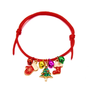 Detail of red braided Christmas bracelet with bells and festive enamel charms