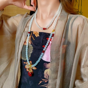 Detail of beaded tassel necklace with red gourd charms and pale green glass beads