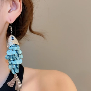 Detail of fish-shaped shell tassel earring with blue sequin scales and silver hooks