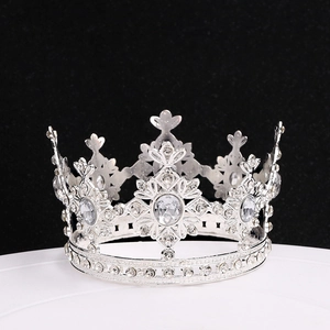 Detailed close-up of sparkling silver alloy crown with rhinestones on a white pedestal