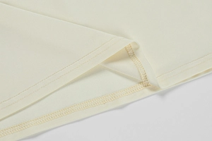 Close-up of double-stitched hem and overlock seam on beige knit dress fabric
