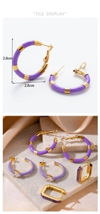 Detail view of 2.8cm C-shaped gold hoops with purple zircon hearts and enamel texture