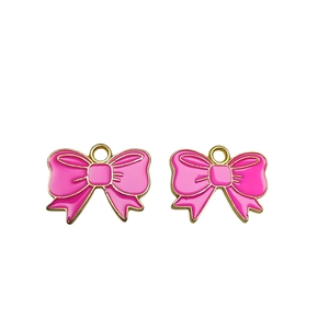 Close-up of pink enamel bow charms with gold metal frames and hanging loops