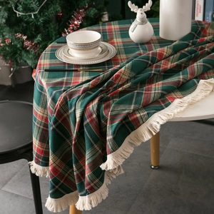 Classic green and red plaid Christmas tablecloth with white fringe tassels on a round table