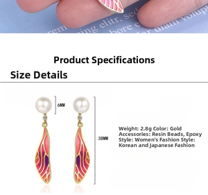 Detailed close-up of gradient cicada wing earrings with white pearls and gold accents