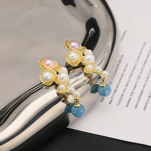 Detail of floral gold earrings with white pearls, pink pearls, and blue bead drops