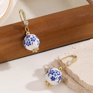 Vintage blue and white porcelain bead earrings with gold accents on stone display