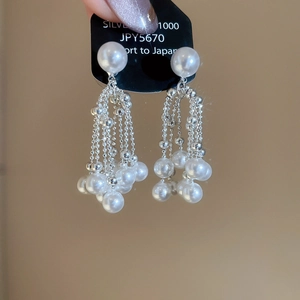 Detail of silver drop tassel earrings featuring delicate pearl clusters and 1000 silver finish