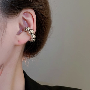 Vista dettagliata di un ear cuff con perline d'argento indossato con finitura lucida