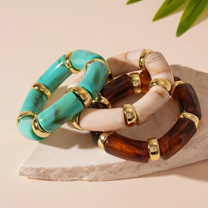 Three-piece acrylic bamboo stretch bracelets in amber, cream, and turquoise marble with gold beads