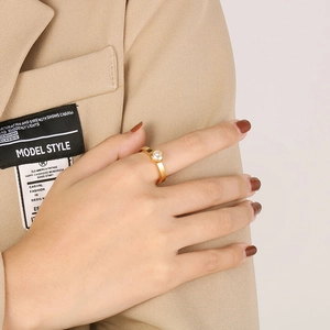 Détail d'une bague dorée avec zircon portée avec une tenue professionnelle beige élégante