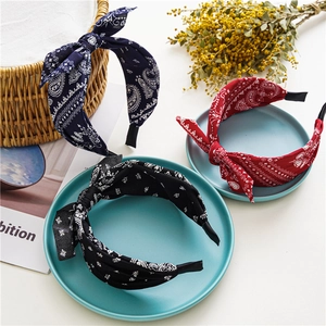 Three paisley bow headbands in navy, red, and black colors on decorative trays