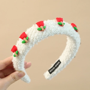 Detail of white plush headband with red clay roses and green leaves, handmade label