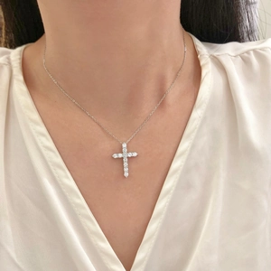 Elegant silver cross pendant necklace with sparkling cubic zirconia on female model