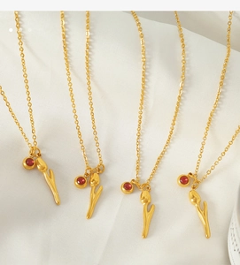 Detailed view of four 18k gold plated tulip necklaces with red zircons on white silk