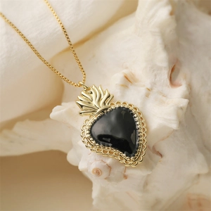 Vintage heart pendant necklace with black enamel crown and gold chain on sea shell